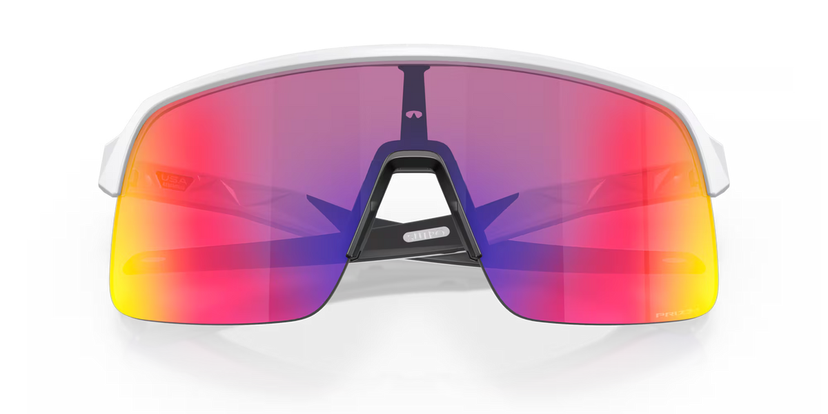 Oakley Sutro Lite Matte White Prizm Road sports sunglasses, front view with crossed white temples visible through the lenses.