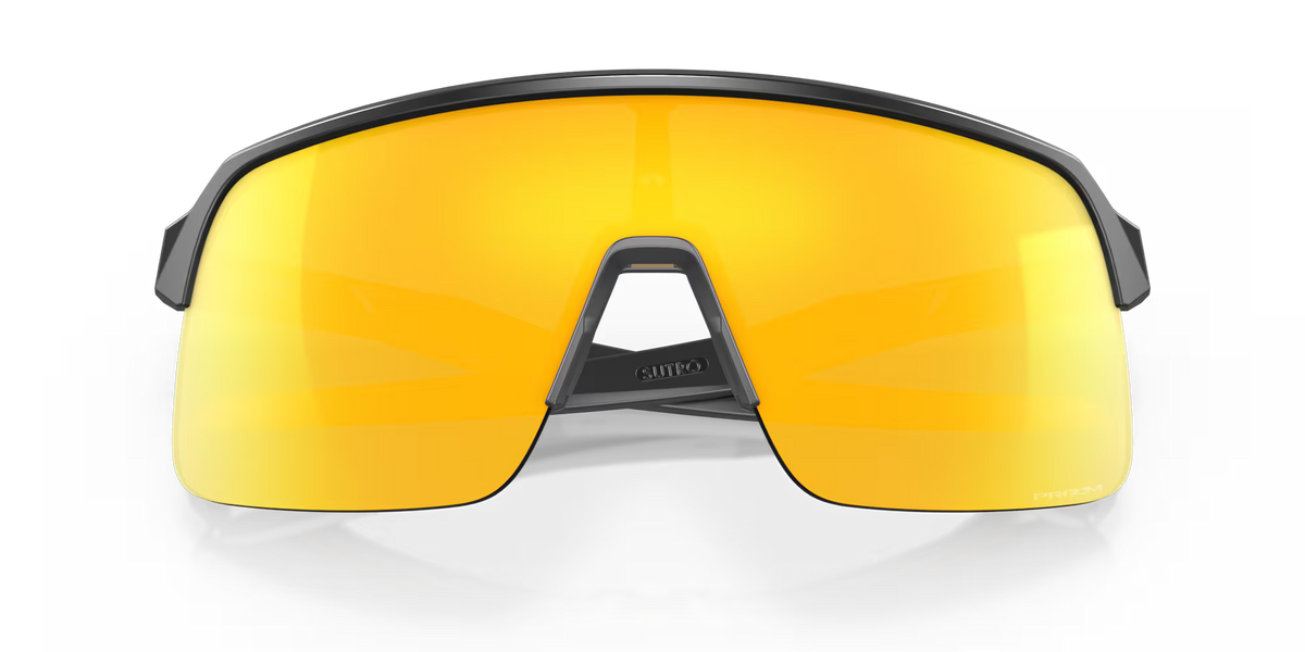 Oakley Sutro Lite Matte Carbon Prizm 24K sports sunglasses, front view with crossed carbon-grey temples visible through the gold lenses.