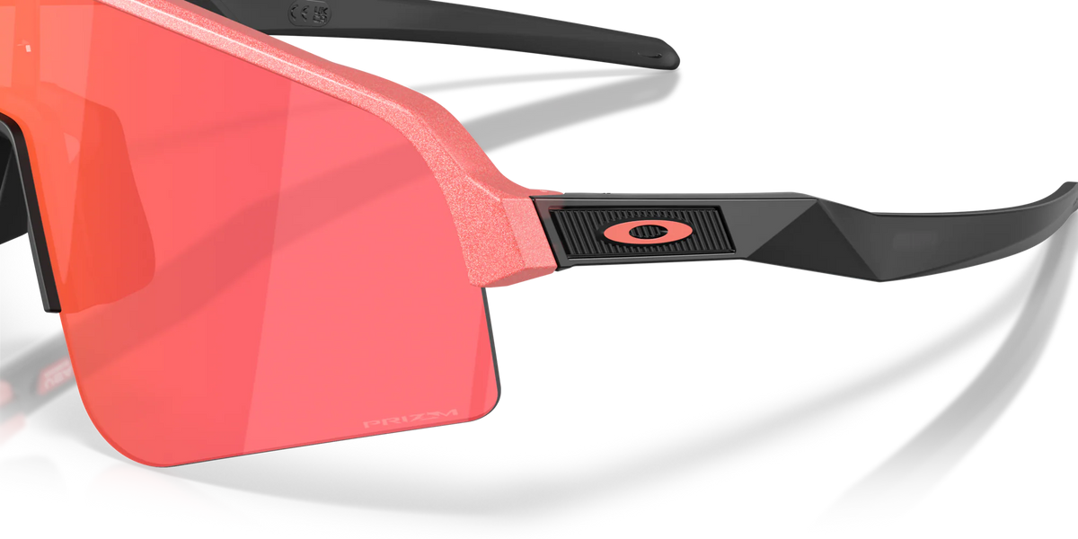 Gros plan sur les lunettes Oakley Sutro Lite Sweep Muted Metallic Paloma Prizm Trail Torch, mettant en évidence le logo Oakley, les finitions métalliques de la monture et les verres rosés.