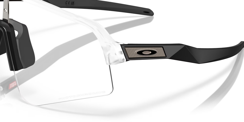 Gros plan sur les lunettes Oakley Sutro Lite Sweep Matte Clear Photochromic, mettant en évidence le logo Oakley, la monture transparente, les branches noires et les verres photochromiques.
